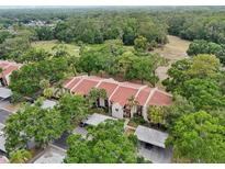 Aerial view of condominium with red tile roof, carports, and mature landscaping at 3505 Tarpon Woods Blvd # K409, Palm Harbor, FL 34685