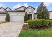Charming home featuring a stone facade, well-maintained landscaping, and a brick driveway leading to the garage at 4195 Barletta Ct, Wesley Chapel, FL 33543
