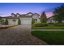 Beautiful exterior view of home with stone accents, three-car garage, and a well-maintained lawn at 4195 Barletta Ct, Wesley Chapel, FL 33543