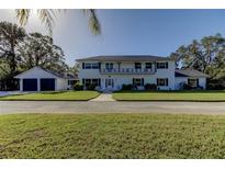 Charming two-story home with a balcony, dark shutters and a two-car garage on a manicured lawn at 1089 Virginia St, Dunedin, FL 34698