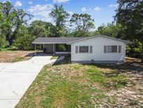Charming single-story home with a covered front porch, a long driveway, and an expansive front yard at 11409 Spring Hill Dr, Spring Hill, FL 34609