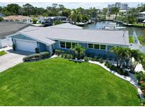 Beautiful waterfront home featuring a manicured lawn, lush landscaping, and a private boat dock, perfect for outdoor living at 1769 Brookside Blvd, Largo, FL 33770