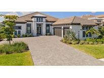 Stunning home featuring a brick driveway, neutral color palette, a two-car garage, and meticulously landscaped yard at 3888 Santa Caterina Blvd, Bradenton, FL 34211