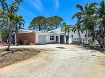 Charming home featuring a brick accent wall, an attached garage, and mature tropical landscaping at 719 59Th Ave, St Pete Beach, FL 33706