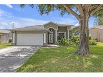 Charming single-story home with lush landscaping, attached garage, and welcoming front entrance at 7246 Julian St, New Port Richey, FL 34653