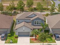 This aerial shot displays a well-maintained two-story home with a gray exterior, complemented by lush landscaping and a two-car garage at 10623 Bahama Woodstar Ct, Riverview, FL 33579