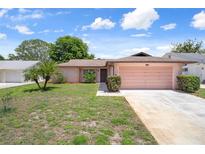 Charming single-story home featuring an attached garage, well-maintained lawn, and lovely landscaping at 10820 Hachita Dr, Port Richey, FL 34668