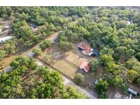 Aerial shot captures a sprawling estate with a well-maintained home, barn, and refreshing pool surrounded by nature at 12311 Oakwood Dr, Hudson, FL 34669