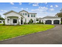 Beautiful two-story white home with manicured lawn and attached three car garage at 13711 Lussier Ln, Spring Hill, FL 34610