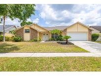 Charming home featuring mature landscaping, a well-manicured lawn, and an attached two-car garage at 1426 Buckner Rd, Valrico, FL 33596