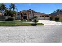 Charming single-story home with a well-manicured lawn and a three-car garage on a sunny day at 18104 Sweet Jasmine Dr, Tampa, FL 33647