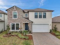 Charming two-story home featuring stone accents, a two-car garage, and a beautifully landscaped front yard at 22294 Storybook Cabin Way, Land O Lakes, FL 34637