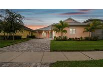 Charming peach colored exterior with tidy lawn, paver driveway, and palm trees at 2973 Breezy Meadows, Clearwater, FL 33760