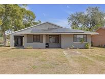Charming single-story home featuring solar panels, gray exterior paint, and well-manicured landscaping at 4623 Wisteria Dr, Zephyrhills, FL 33542