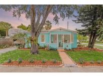 Charming turquoise home with a cozy front porch, mature landscaping, and a lush green lawn at 653 E Spruce St, Tarpon Springs, FL 34689
