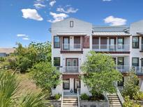 Beautiful townhome with white trim, a pair of balconies, and mature trees in the front yard at 946 Highland Ave # 24, Dunedin, FL 34698