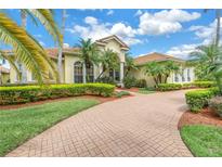 Stunning Mediterranean-style home with lush landscaping, a brick driveway and a barrel tile roof at 9818 Tree Tops Lake Rd, Tampa, FL 33626