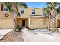 Inviting townhouse exterior featuring a one-car garage, palm trees, and manicured landscaping at 9960 Hound Chase Dr, Gibsonton, FL 33534