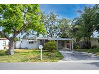 Modest single-story home with mature trees and a covered carport and front patio at 10570 114Th Ter, Largo, FL 33773