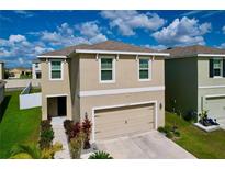 Two-story home with a beige exterior, two-car garage, manicured landscaping, and a blue sky above at 11013 Leland Groves Dr, Riverview, FL 33579