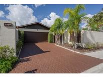 Charming single-Gathering home with a brown two-car garage and brick paved driveway lined with tropical landscaping at 13511 Avista Dr, Tampa, FL 33624