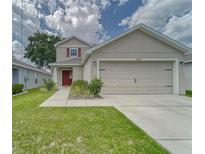 Charming two-story home with a well-manicured lawn, showcasing its inviting curb appeal and attached two car garage at 13822 Harvestwood Ln, Riverview, FL 33569