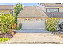 Exterior image of a two-car garage with a concrete driveway, lush landscaping, and clear house number at 13934 Clubhouse Cir # 8, Tampa, FL 33618