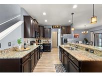 Modern kitchen featuring dark cabinets, granite countertops, stainless steel appliances, and a spacious island at 1726 Hadden Hall Pl, Trinity, FL 34655