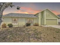 Charming one-story home featuring an attached garage and a well-maintained front yard with a beautiful sunset in the background at 2816 Manor Hill Dr, Brandon, FL 33511