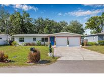 Charming single-story home with a well-manicured lawn, blue door, and a two-car garage under a clear blue sky at 308 Jeanal Pl, Tampa, FL 33612