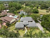Stunning aerial view of home with lush landscaping, pool, water feature, and golf course in the distance at 4009 Carrollwood Village Dr, Tampa, FL 33618