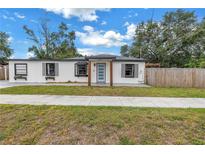 Charming single-story home with a well-manicured lawn and a modern, updated facade, and a light blue front door at 4432 W Mccoy St, Tampa, FL 33616