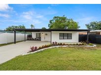 Charming single-story home featuring a covered parking area, a fresh green lawn, and beautifully manicured landscaping at 4681 70Th N Ave, Pinellas Park, FL 33781