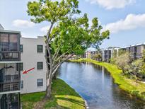 Condo building overlooking a tranquil lake, surrounded by lush greenery and mature trees under a bright, sunny sky at 5980 Terrace Park N Dr # 214, St Petersburg, FL 33709