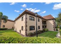 Two story condo building with brown trim, green grass, and well maintained landscaping at 12900 Vonn Rd # F101, Largo, FL 33774