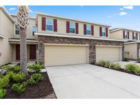 Townhome boasts stone accents, neutral paint, garage, and well-maintained landscaping at 13233 Canopy Creek Dr, Tampa, FL 33625
