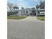 Charming single-story home with covered parking, a well-maintained lawn, and vibrant yellow trim at 135 143Rd E Ave, Madeira Beach, FL 33708