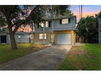 Two-story home with white and yellow siding, green shutters, attached garage, and mature trees in the front yard at 1810 Maryland Ne Ave, St Petersburg, FL 33703