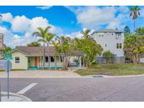 Inviting coastal home with covered porch, manicured landscaping, and paved driveway entrance at 18198 3Rd E St, Redington Shores, FL 33708
