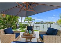 Relaxing outdoor patio with woven seating, blue cushions, and a stunning view of the water at 243 Hermosita Dr, St Pete Beach, FL 33706