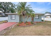 Charming single-story home featuring a red driveway, mature palm trees, and tidy landscaping at 3308 W Walnut St, Tampa, FL 33607