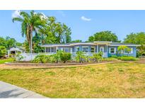 Beautiful single Gathering home with well-manicured lawn, mature landscaping, and a decorative white fence along the front of the property at 401 Whitcomb Blvd, Tarpon Springs, FL 34689
