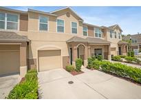 Two-story tan townhome with a one-car garage, green bushes and well maintained driveway at 6912 40Th N Ln, Pinellas Park, FL 33781