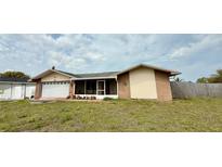 Ranch-style home featuring an attached two-car garage and a screened-in patio at 7012 Pin Cherry Ln, Port Richey, FL 34668