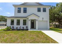 Charming two-story home with white siding, black trim, manicured lawn and driveway at 925 E Chelsea St, Tampa, FL 33603