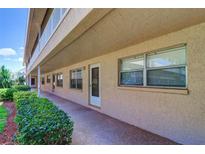 Exterior view of condo with neutral stucco siding, walkway, and green shrubs along the front at 10037 62Nd N Ter # 9, St Petersburg, FL 33708