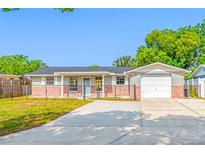Charming single-story home featuring a gray facade with brick accents and well-manicured lawn at 10825 Oakdale Ave, Port Richey, FL 34668