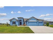 Charming blue single-story home with a well-manicured lawn and a three-car garage at 12710 Wheatgrass Ct, Parrish, FL 34219