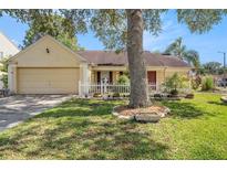 Charming single-story home with a manicured lawn, white picket fence, and a two-car garage at 16201 Country Crossing Dr, Tampa, FL 33624
