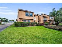 Exterior view of a two-story townhouse with neutral stucco, green lawn, and well-maintained landscaping at 1864 Clearbrooke Dr, Clearwater, FL 33760